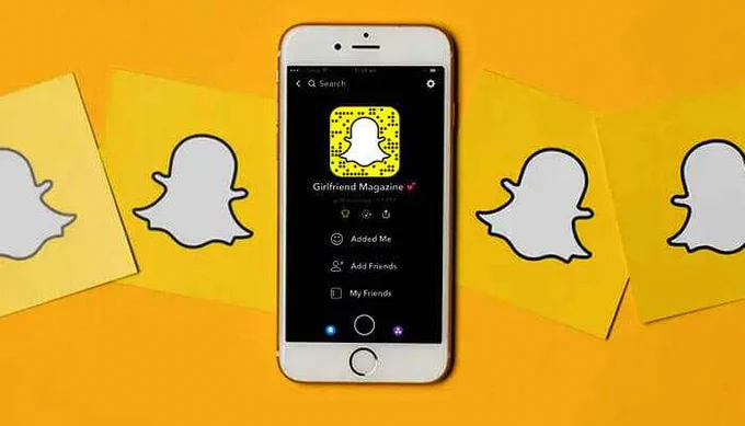 Snapchat app open on an iPhone showing a Snapchat profile with a Girlfriend Magazine username, surrounded by yellow Snapchat logos.