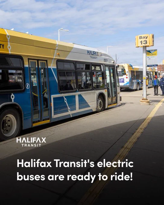 Alt text: A Halifax Transit electric bus parked at a bus bay at Bridge Terminal. Several people and another bus are visible in the background. There is a Halifax Transit logo at the bottom of the image, above text that reads: “Halifax Transit’s electric buses are ready to ride!”
