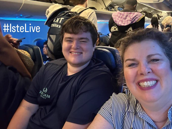 Two people smile inside an airplane