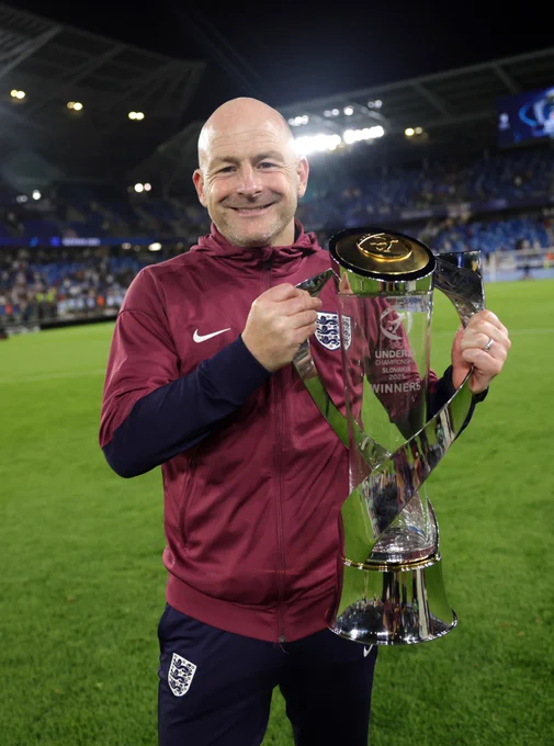 Lee Carsley holds the U21 EURO trophy on the pitch with pride. 