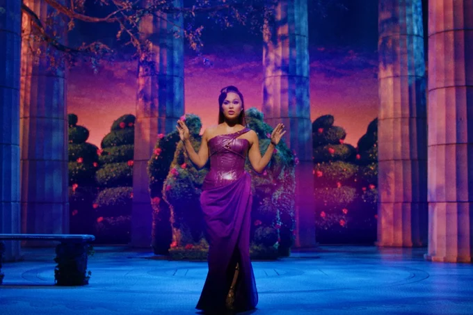 A photo showing a woman in a purple dress posing on a stage 
