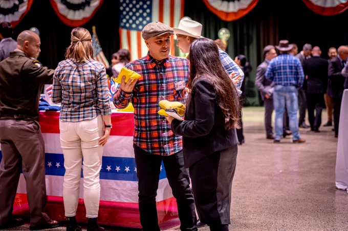 Guests dressed in checkered shirts playfully engage in a corn hole game, capturing the fun spirit of the fair-themed celebration.