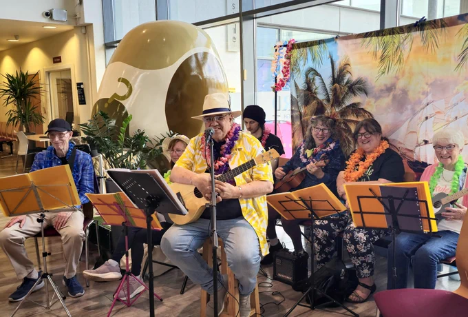 Band members at the Volunteer Fair. A man in the centre of the photo wears a yellow shirt and has a ukulele. 