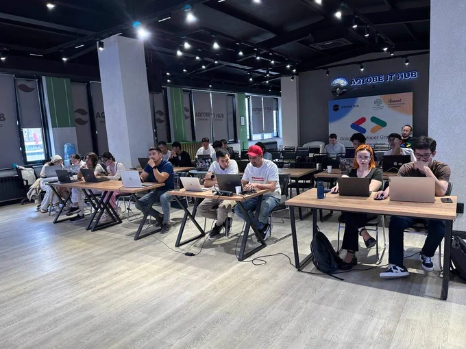 A group of people study their screens at a local Build with AI event.