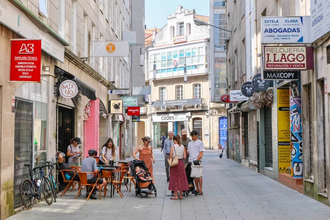 People of all ages and abilities walk, cycle, sit, and socialise on the car-free streets of Pontevedra, which are lined with buildings, trees, benches, and patios.