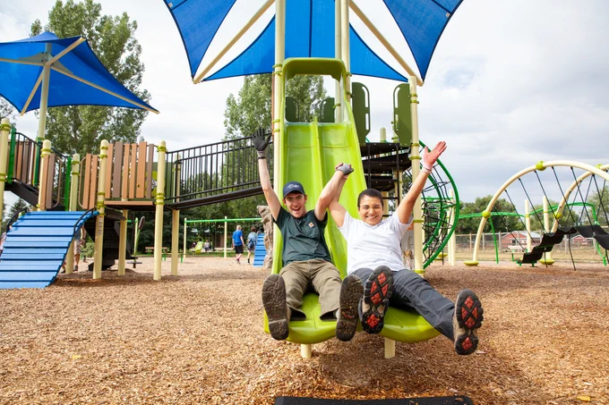 Two people sliding down a slide