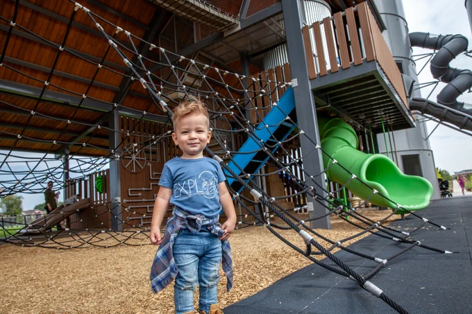 A little boy posing in front of a playground