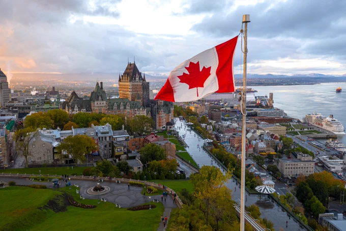A Canadian flag flies high at sunset with Old Quebec City 