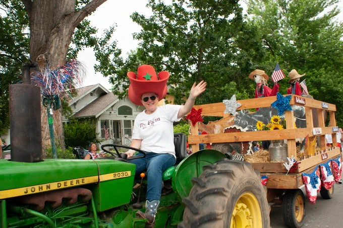 A tractor pulls a float in a 4th of July parade
