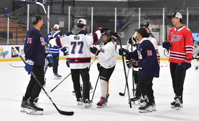 Photo of Michael Misa and Simon Wang celebrating with a kid with other skaters around him on ice