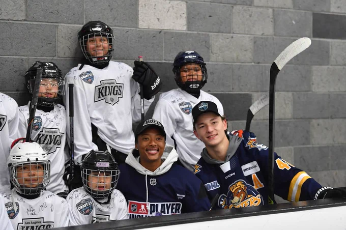 Photo of Matthew Schaefer posting for a photo with multiple kids and people on the bench