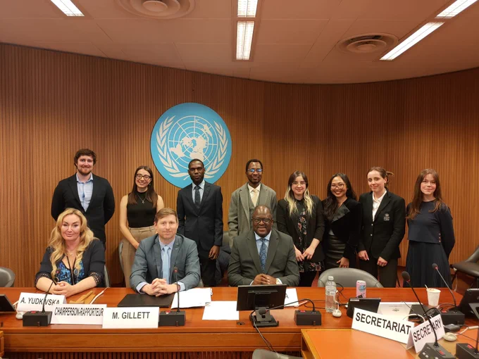People standing together with the United Nations symbol behind them.