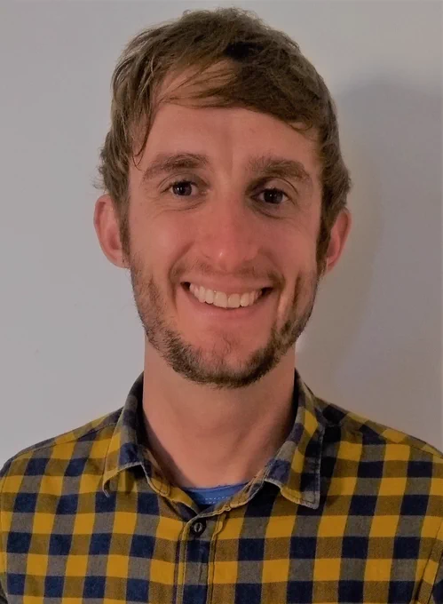 Man smiling in a checked black and yellow shirt.