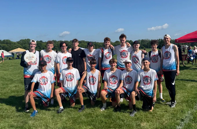 Team photo of U17 team Illinois Nightmare. 14 players and 2 coaches pose on a field in team apparel.