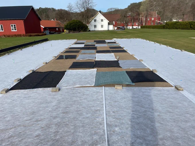 A turfgrass research area with some plots uncovered and other plots covered in different permeable spring covers. 