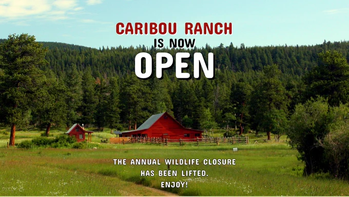A scenic view of Caribou Ranch with green meadows, tall pine trees, and a red barn nestled in the valley under a blue sky. Bold text reads: "Caribou Ranch is now OPEN." Below, it says: "The annual wildlife closure has been lifted. Enjoy!"