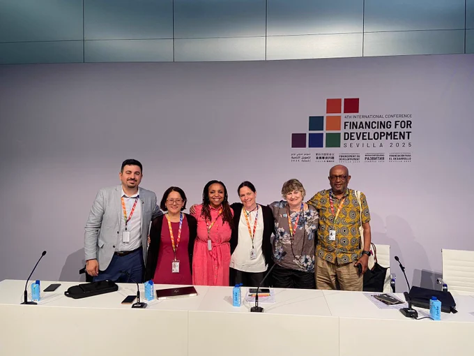 Image of six people standing in front of a panel. 