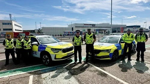 Picture of several uniformed police officers standing next to two marked police vehicles outside Aberdeen Airport.