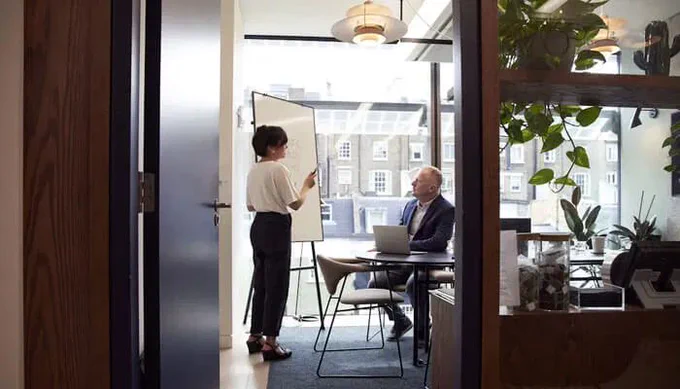 Business professionals in a modern office discussing a presentation on a whiteboard, representing the power of automation in workplace efficiency.