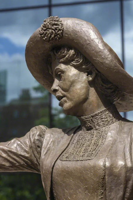 Close up of a bronze sculpture of Emmeline Pankhurst. She is mid-speech, with one arm out.