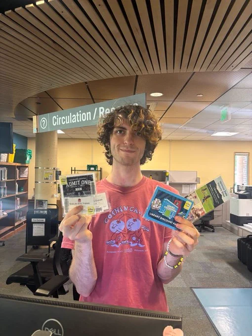 A person holding museum and historic site passes behind the circulation desk in Howe Library.