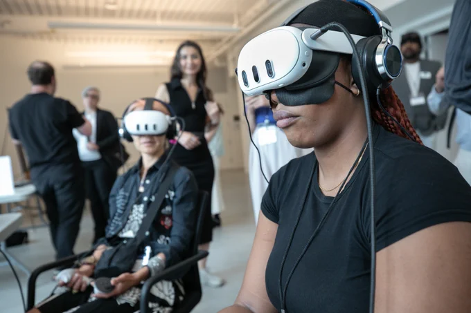 Two attendees wear virtual reality headsets and looks of intense concentration.
