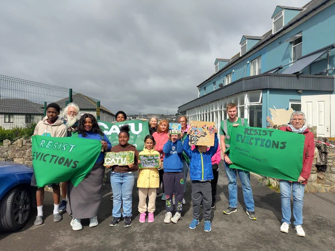 A photo of CATU members, residents, and locals holding up signs and flags.