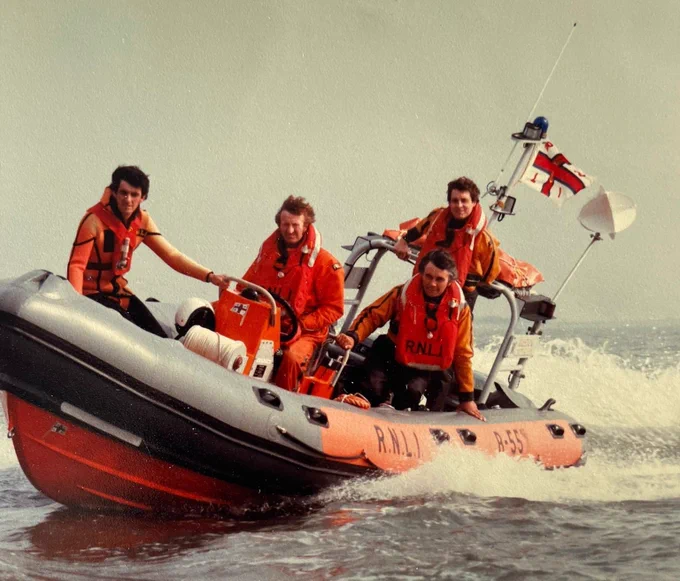 Four RNLI crew members on a inshore lifeboat at sea, smiling and looking towards the camera.