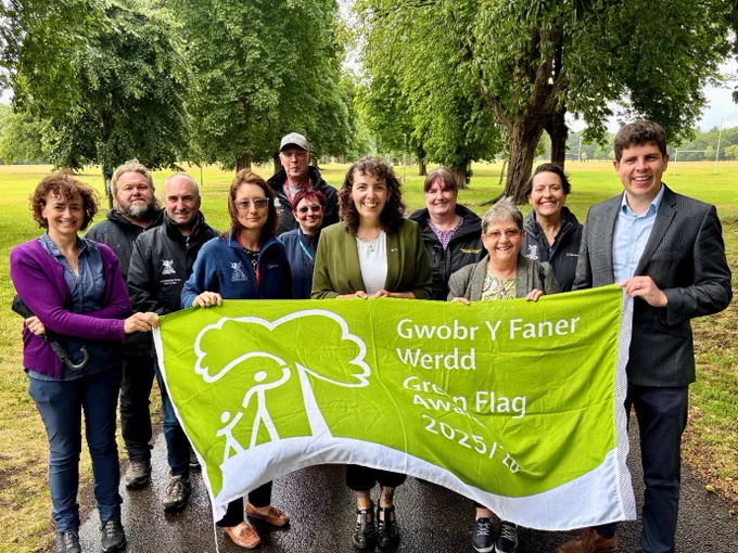 A group of people holding a large green flag.