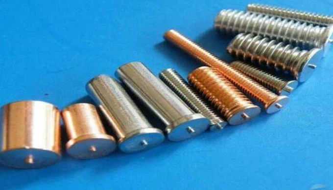 Assorted metallic welding studs arranged on a blue surface, showcasing product variety and quality from a reliable Welding Studs Supplier.