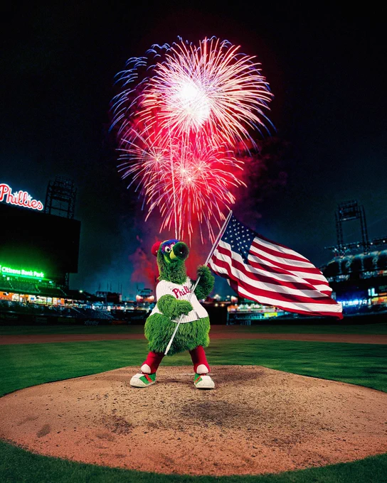 Phanatic waves an American flag on the mound while fireworks go off behind him.