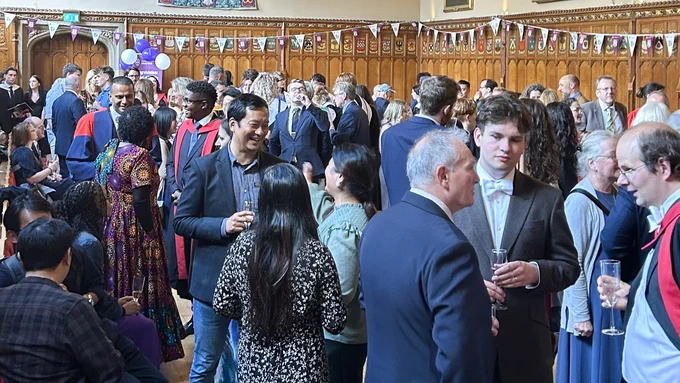 Colour photo of many people speaking throughout Rainy Hall.
