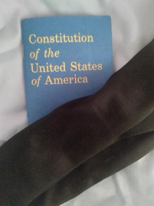 a "Constitution of the United States of America" booklet with a black scarf draped diagonally across the bottom 