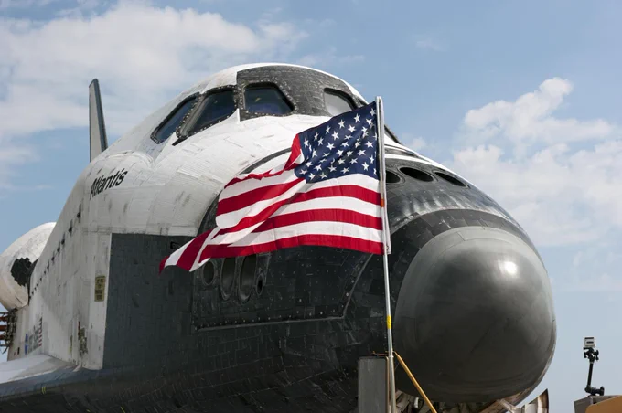 An American flag waves in the wind in front of space shuttle Atlantis on the Shuttle Landing Facility's Runway 15 at NASA's Kennedy Space Center in Florida. Atlantis' final return from space at 5:57 a.m. (EDT) on July 21, 2011, completed the 13-day, 5.2-million-mile STS-135 mission. Photo credit: NASA