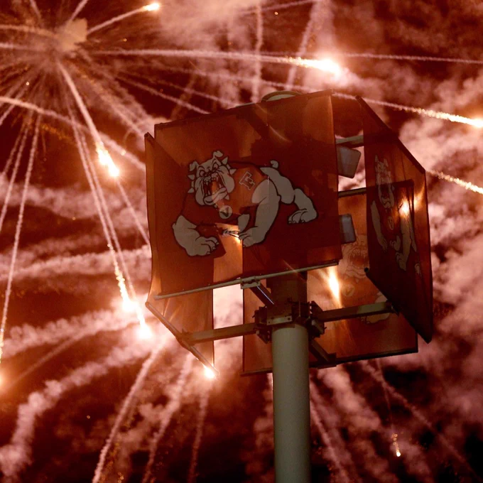 Fireworks display behind a traffic light with the Fresno State Bulldog logo.