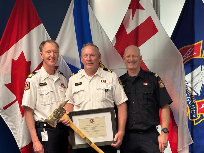 from left: Deputy Chief Dave Meldrum, Division Chief of Training Vince Conrad, and Training Officer Brian Rogers. Vince is holding his retirement certificate and ceremonial axe. 