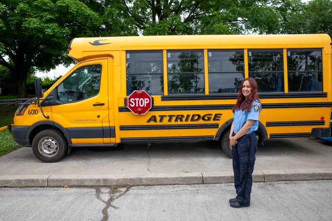 Kenzie Van Wagner, Safety Village Coordinator at the Halton Regional Police Service’s Children’s Safety Village, standing beside the Attridge Transportation school bus donation.
