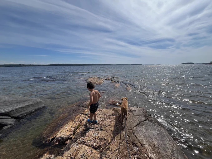 A child and a dog standing on a rocky shore of Georgian Bay.