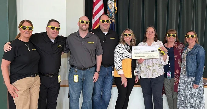 A group of people posing for a photo wearing yellow glasses. 