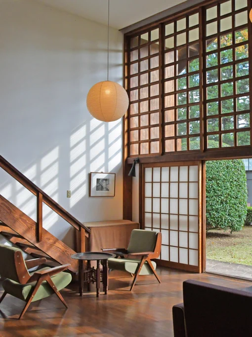 A modern Japanese interior featuring lots of wooden textures and a floor-to-ceiling view of the garden outside.