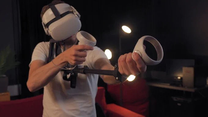 Person wearing a VR headset and holding a stock with VR controllers mounted to it to simulate a rifle or other long, two handed firearm.