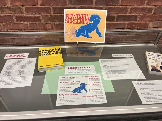 Flat display case with books and labels about newborn screening