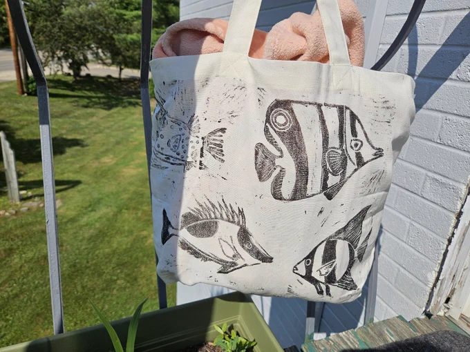 Canvas tote bag with linocut prints of spadefish, rabbitfish, butterfly fish, and boxfish