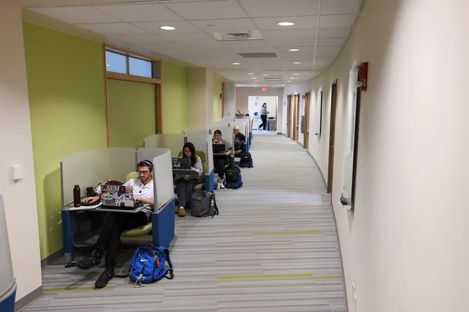 A row of students sit in study pods in a hallway of dana health sciences library.
