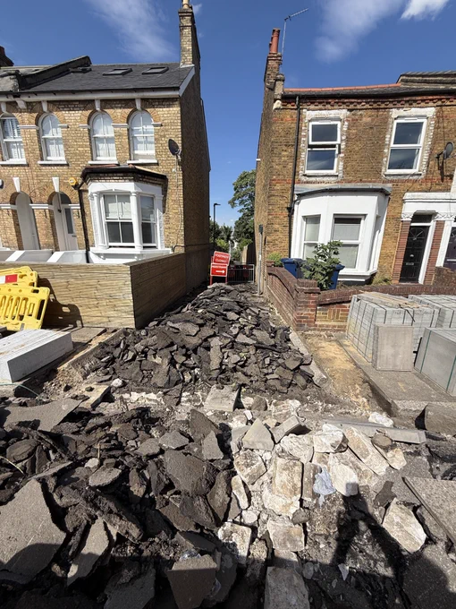 Construction work - a tarmac path has been dug up and is surrounded yellow and red construction barriers and signs. 