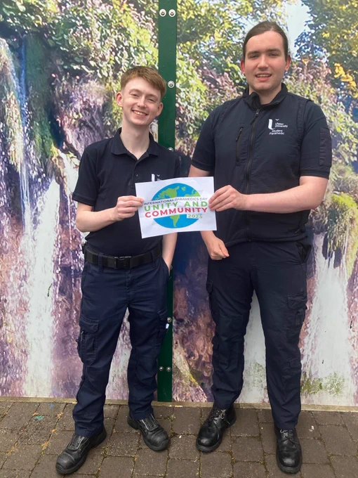 Two student paramedics holding a poster which says Unity and Community.