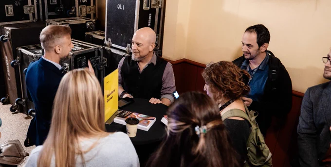 UX Consultant, Author and Speaker Joe Natoli answering questions with a group of young design and UX professionals backstage after a keynote speech.
