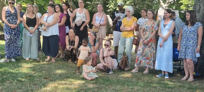 Groupe de parents et enfants dans la pelouse écoutant un discours.