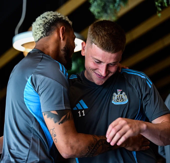 Joelinton and Harvey Barnes embrace at the training ground with Harvey smiling. 