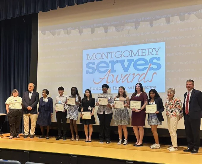 Group of award recipients standing on stage holding certificates at the Montgomery Serves Awards ceremony honoring community service.